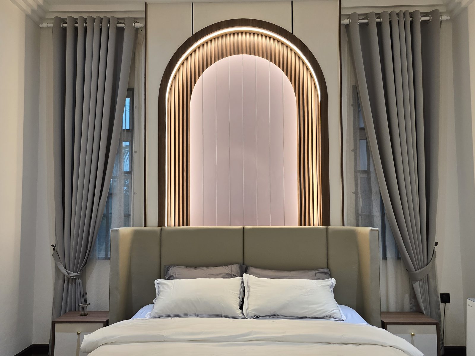 Master bed with arched backlit upholstered headboard