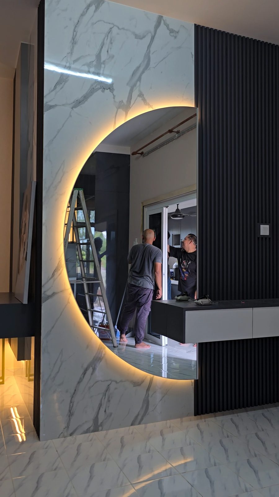 Backlit half-moon mirror on a marble and fluted wall