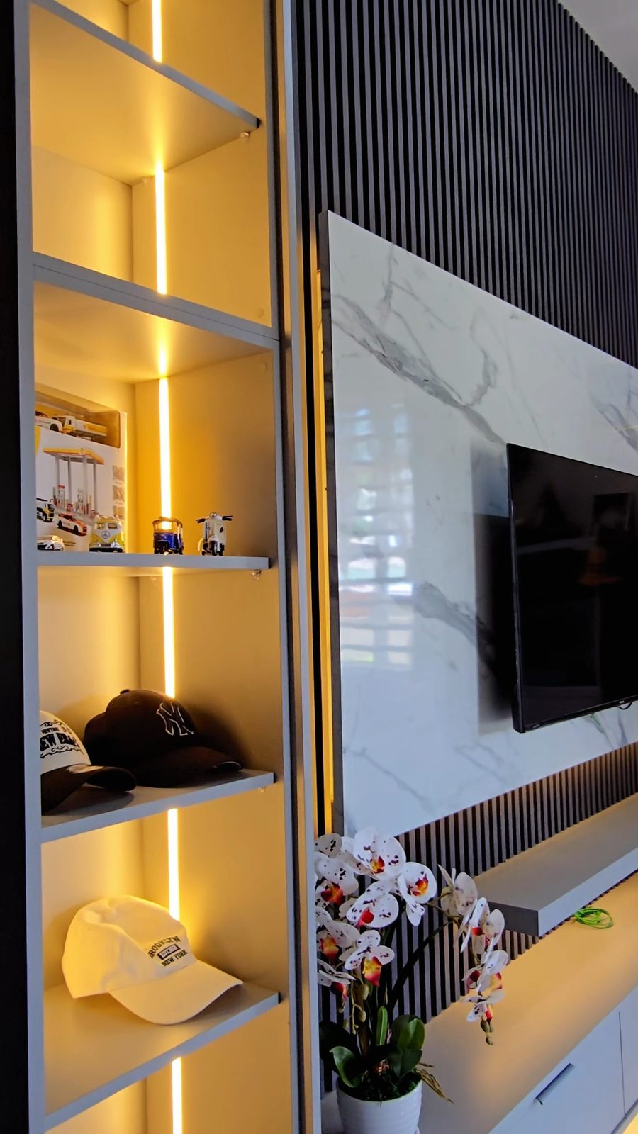 Backlit display shelving beside the TV wall